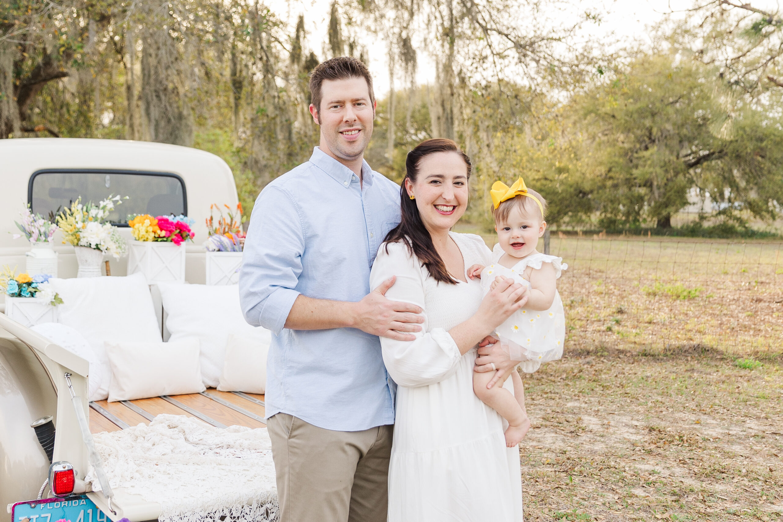 Mom, Dad and baby girl pose by vintage truck for Spring mini session